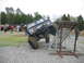 1992 Ford Mustang - A heavily modified Ford Bronco is positioned on a metal obstacle course ramp, with other vehicles and spectators present.