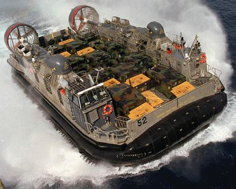 Hovercraft with number 52 on side, carrying military vehicles