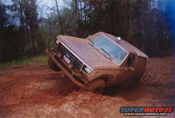 Muddy 1980s Ford Bronco stuck in thick mud off-road