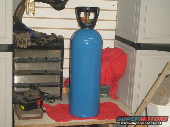 Blue gas cylinder with black regulator and brass fittings