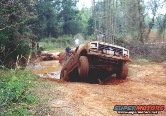 Brown 1980s Ford Bronco stuck in mud, front 3/4 view
