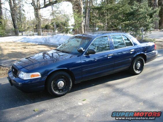 Blue 2003 Ford Crown Victoria sedan parked on asphalt with snow in background