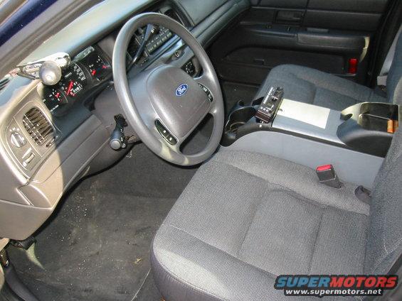 2003 Ford Crown Victoria interior, gray cloth seats, steering wheel with Ford logo, dashboard with gauges