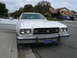 1975 Ford Ranchero - A white 1975 Ford Ranchero with a tan vinyl top is parked curbside with its driver's door ajar.