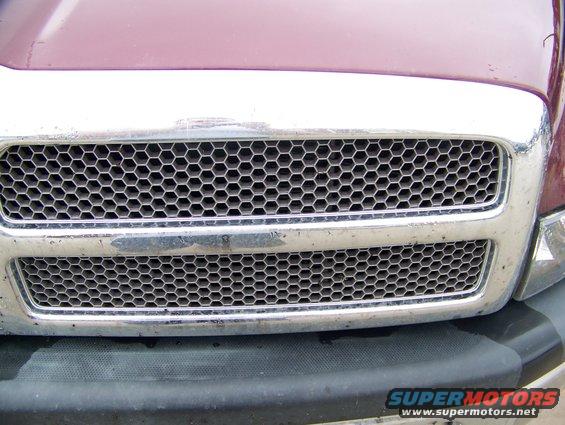 Maroon truck grille with chrome trim and honeycomb pattern. Visible text 'SUPERMOTORS'