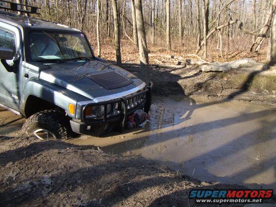 Gray SUV stuck in mud, front 3/4 view