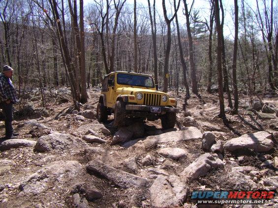 Yellow 2003 Jeep Wrangler navigating a rocky trail