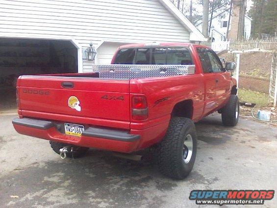 Red 1997 Dodge 1500 pickup truck with a toolbox in the bed and a skull sticker on the tailgate
