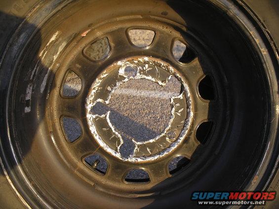 Damaged wheel rim with peeling paint and rust
