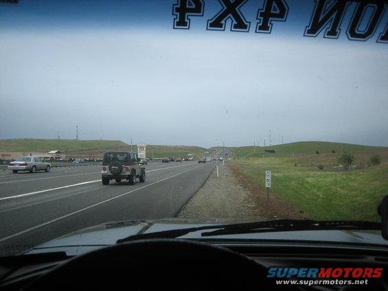 Jeep Wrangler driving on highway, rear view, spare tire on back