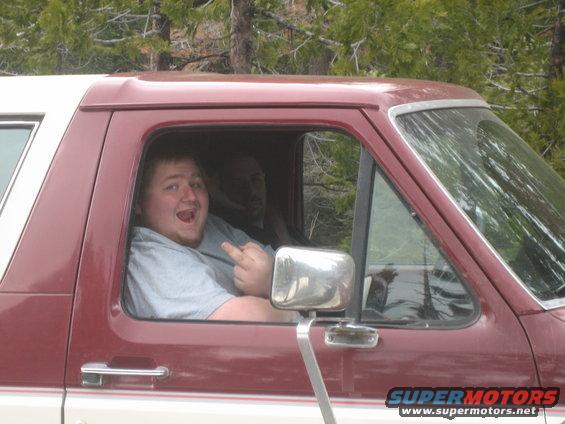 Guy in maroon and white SUV giving middle finger, passenger in background