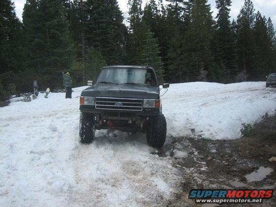 Black Ford truck with lifted suspension driving in snow