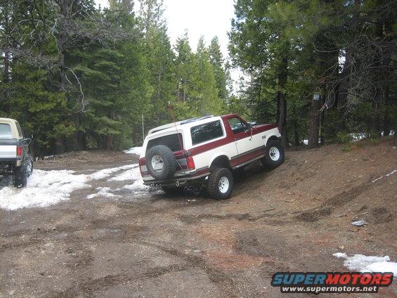 1995 Ford Bronco climbing a dirt hill, another SUV visible to the left