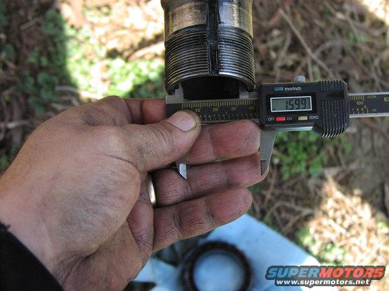 Measuring a threaded metal part with digital calipers showing 1.599 inches