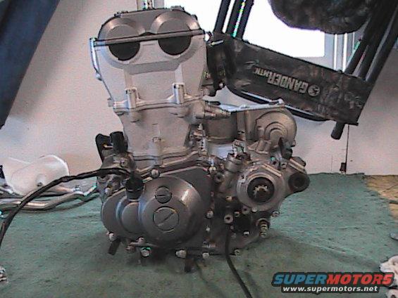 Motorcycle engine on a green mat. Text on a black object reads 'GANDERMATIC'