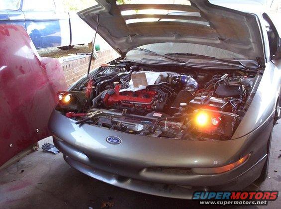 Silver 1995 Ford Probe with hood open, engine exposed, parked next to a red hood and a blue vehicle