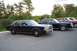1991 Mercury Marquis - Three dark sedans and one red sedan are parked in a lot, with trees in the background.