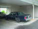 1991 Mercury Marquis - A dark blue sedan is parked under a carport next to another vehicle.