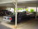 1991 Mercury Marquis - Several cars are parked under a carport, including a dark sedan with a visible license plate.