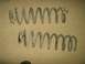 2004 Jeep Wrangler - Two used coil springs are shown against a neutral background, with one exhibiting damage.