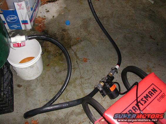 Pump and hoses connected to a bucket, with a Craftsman tool visible