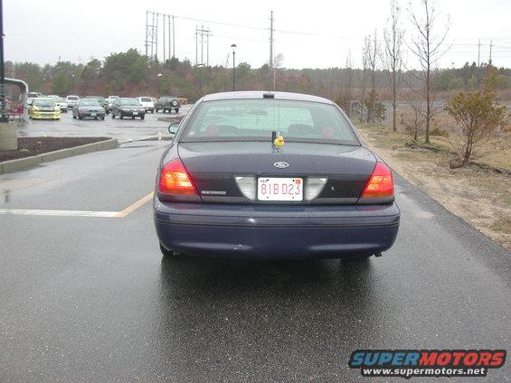 Dark blue sedan, license plate 81B D23, parked on wet asphalt