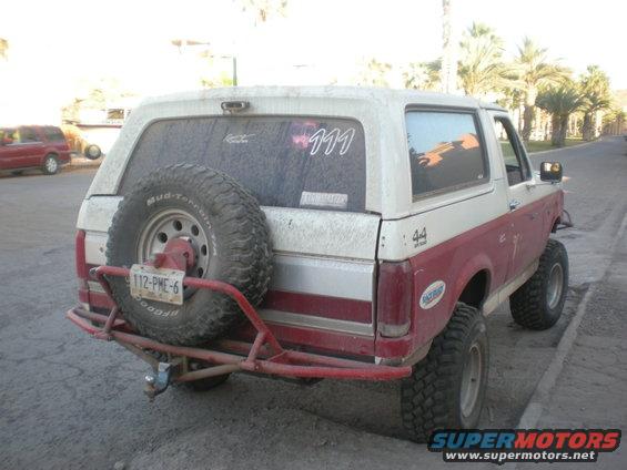 Red and white 1993 Ford Bronco rear view with spare tire and custom bumper