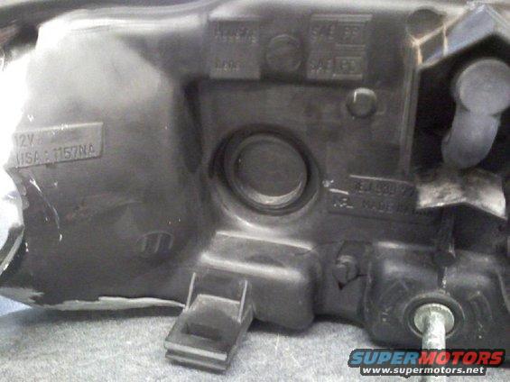 Close-up of a car headlight housing with some text and part numbers visible