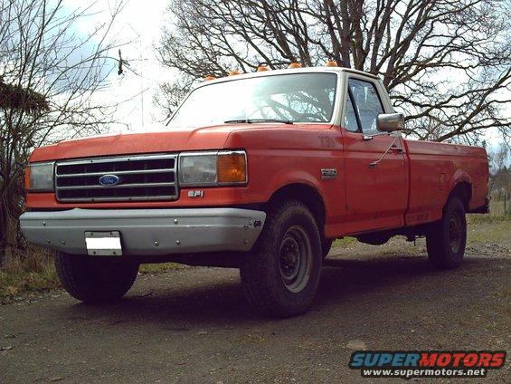 Red and white Ford F-350 truck, front 3/4 view, parked on dirt road