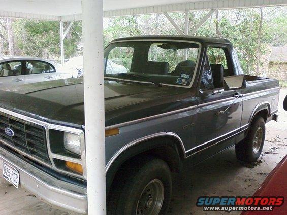 1983 Ford Bronco parked under a carport, with another car visible to the left