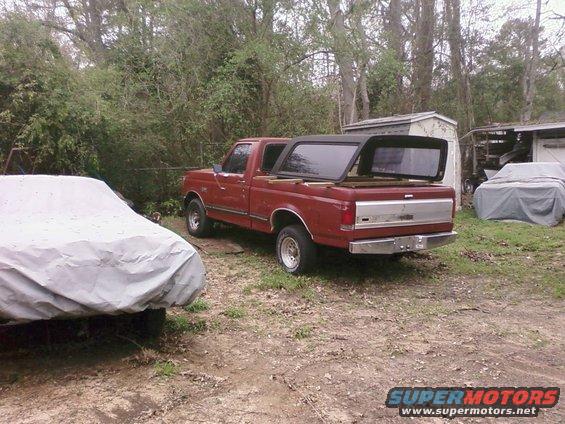 Red 1987 Ford F-150 pickup truck with camper shell, 3q-front view