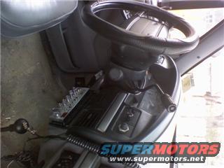 Vehicle interior showing steering wheel, dashboard, and aftermarket control panel