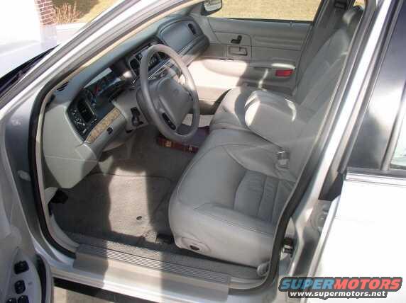 Gray leather interior of a 1998 Ford Crown Victoria, showing the front seats, dashboard, and steering wheel from the passenger side