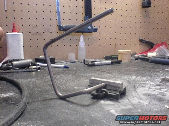 Bent metal rod clamped to a workbench surface