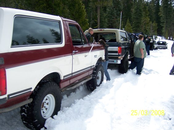 Maroon and white Ford Bronco in snow, lifted with off-road tires