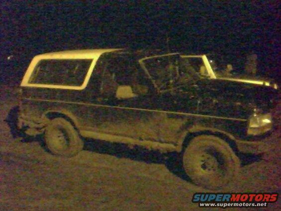 Dark 1993 Ford Bronco with white top, side view