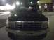 1993 Ford Bronco - The front grille and headlights of a dark SUV are visible at night.