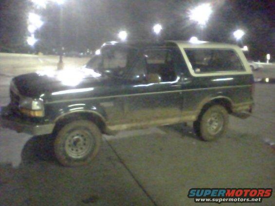 Dark green Ford Bronco with a white removable top, seen at night