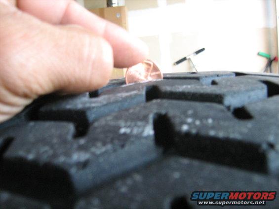 Close-up of tire tread with a penny inserted to check depth