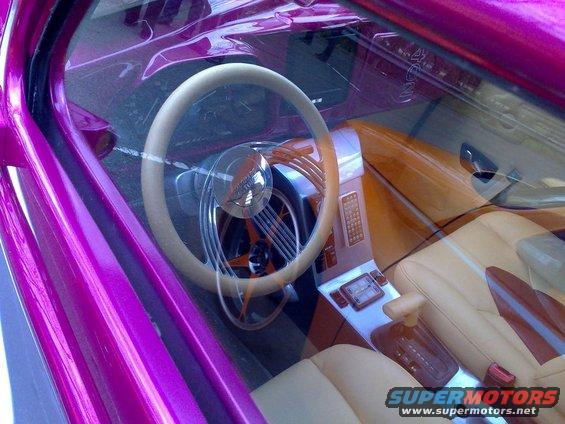 Purple car interior with tan leather seats, custom steering wheel, and dashboard with a screen