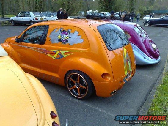 Orange customized PT Cruiser parked next to a purple and silver classic car