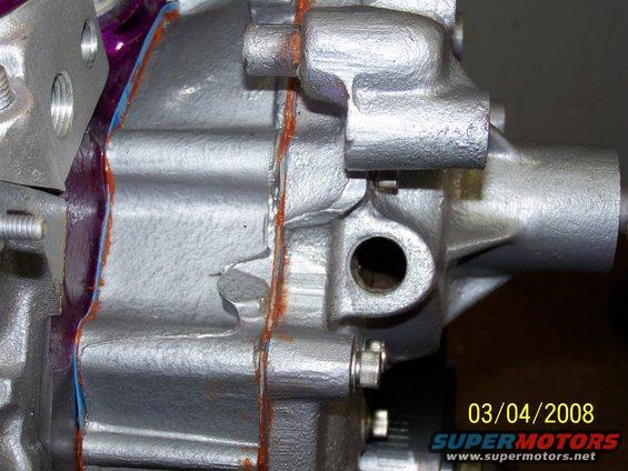 Close-up of silver engine component with orange gasket sealant visible. Date stamp 03/04/2008