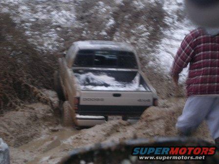 Dodge pickup truck stuck in mud and snow, with a person in a plaid shirt nearby