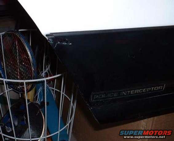 Black car door part with "POLICE INTERCEPTOR" text, next to a basket of items