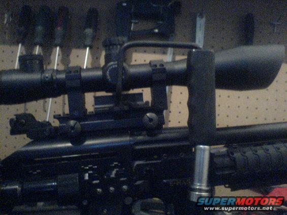 Close-up of a sniper rifle scope with mounting hardware