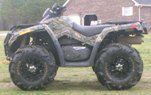 ATV with camouflage body panels and large off-road tires parked on grass