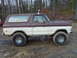 1979 Ford Bronco - A two-tone brown and white Ford Bronco sits on a muddy surface, modified for off-road use.