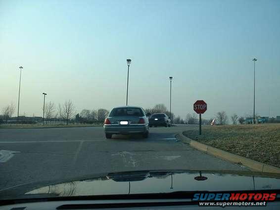 Rear view of a 1998 Ford Crown Victoria driving on a road with another car behind it