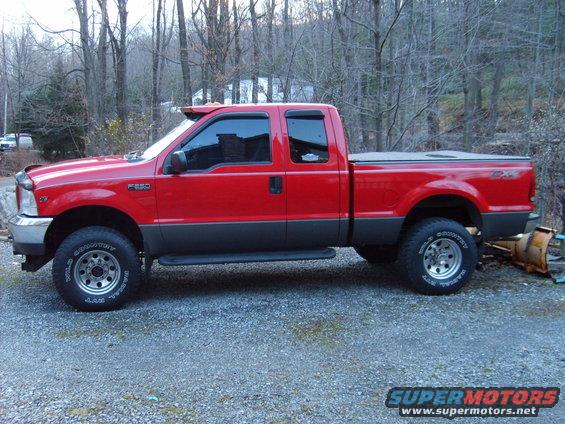 Red 1999 Ford F-250 Super Duty pickup truck, two-tone paint, side view, parked on gravel