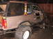 1979 Ford Bronco - This modified SUV is undergoing repairs in a garage, with its front wheel assembly disassembled.